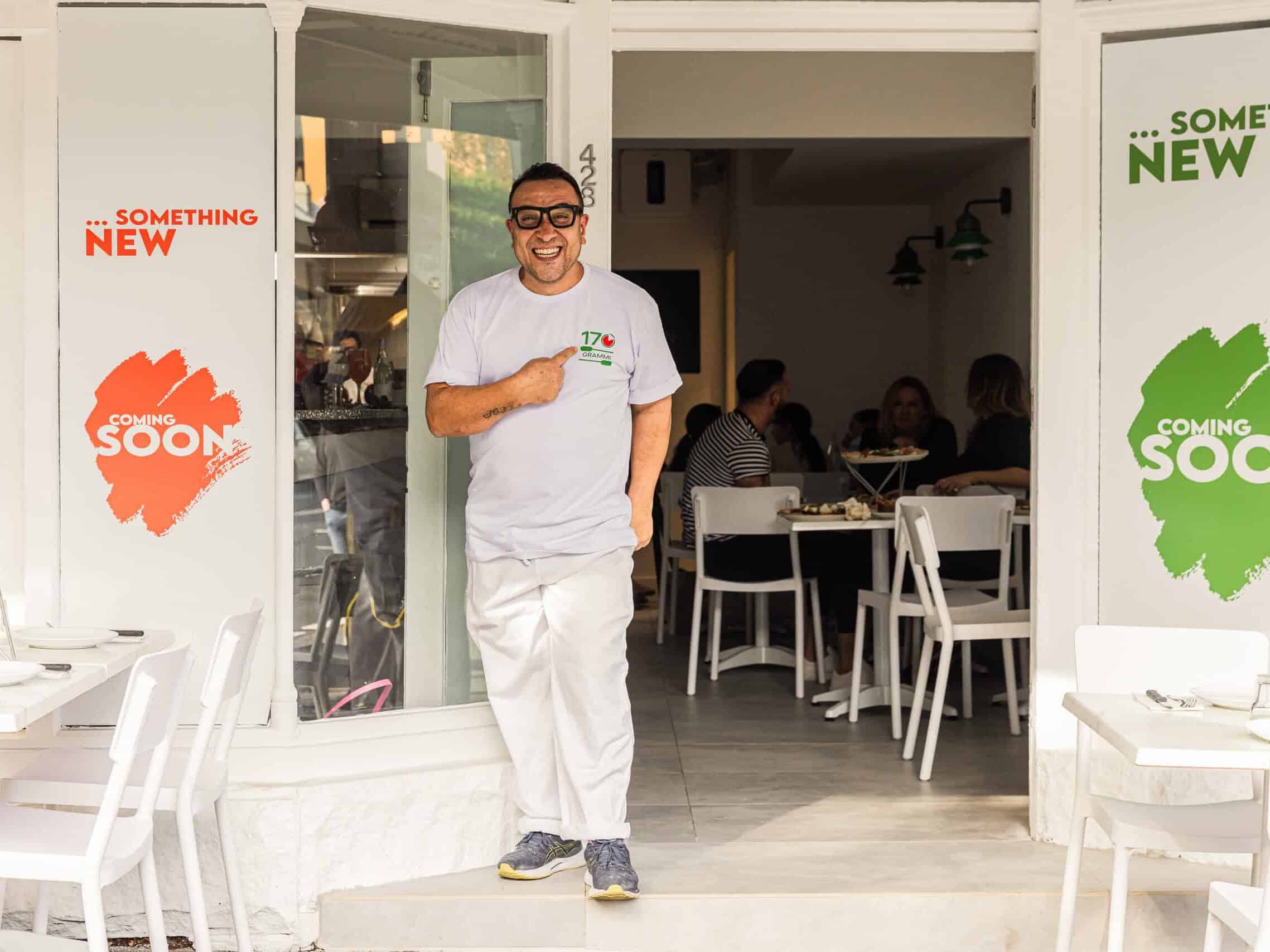 Luigi Esposito outside 170 Grammi Pizzeria pointing to the 170 Grammi logo